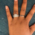 Diamond engagement ring and wedding band on a hand against teal fabric