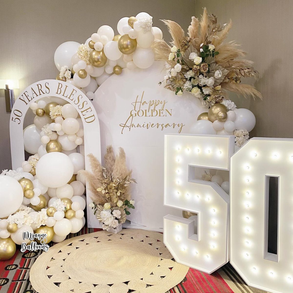 Golden anniversary party decoration with white and gold balloons and illuminated 50 numbers
