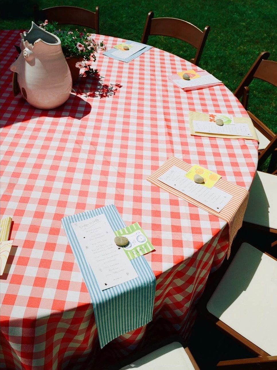 Red and white checkered table setting with menus and flowers in a backyard.