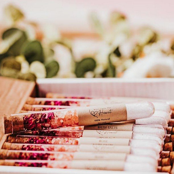 Floral bath salt test tubes with kraft labels arranged in a white tray.