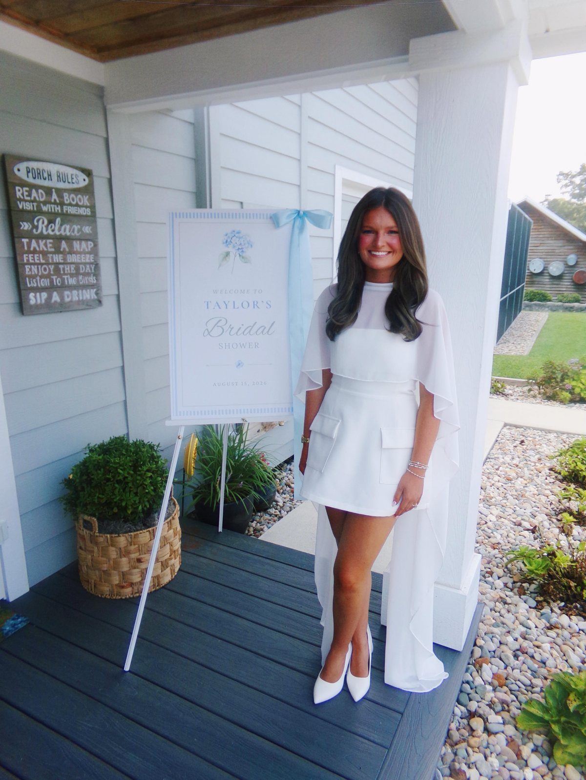 Woman in a short white bridal shower dress with a sheer cape overlay.