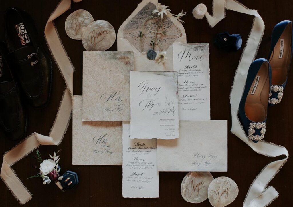 Wedding stationery with elegant script calligraphy surrounded by formal shoes and ribbons.