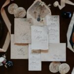 Wedding stationery with elegant script calligraphy surrounded by formal shoes and ribbons.