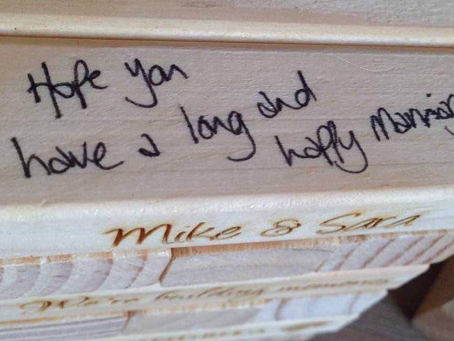 Wooden jenga blocks with handwritten wedding wishes and engraved names Mike and Sara