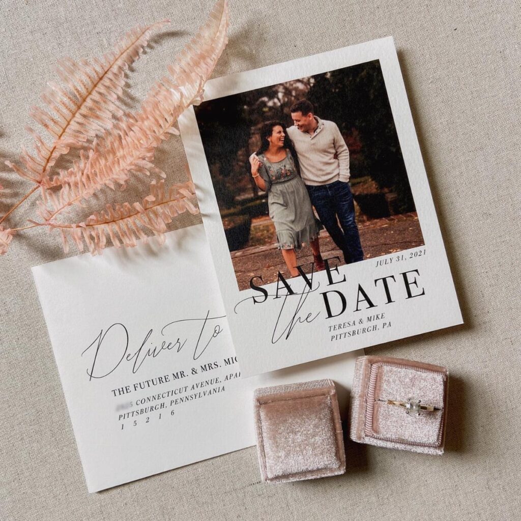 Polaroid style save the date card with a couple, envelope, and velvet ring boxes.