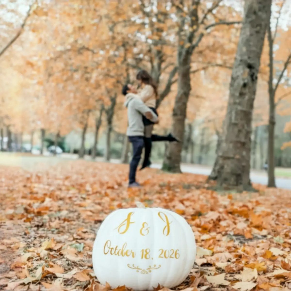 White pumpkin with gold date on a ground covered in orange fall leaves