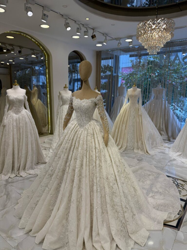 Sparkling white wedding dresses on mannequins in a luxury bridal boutique setting.