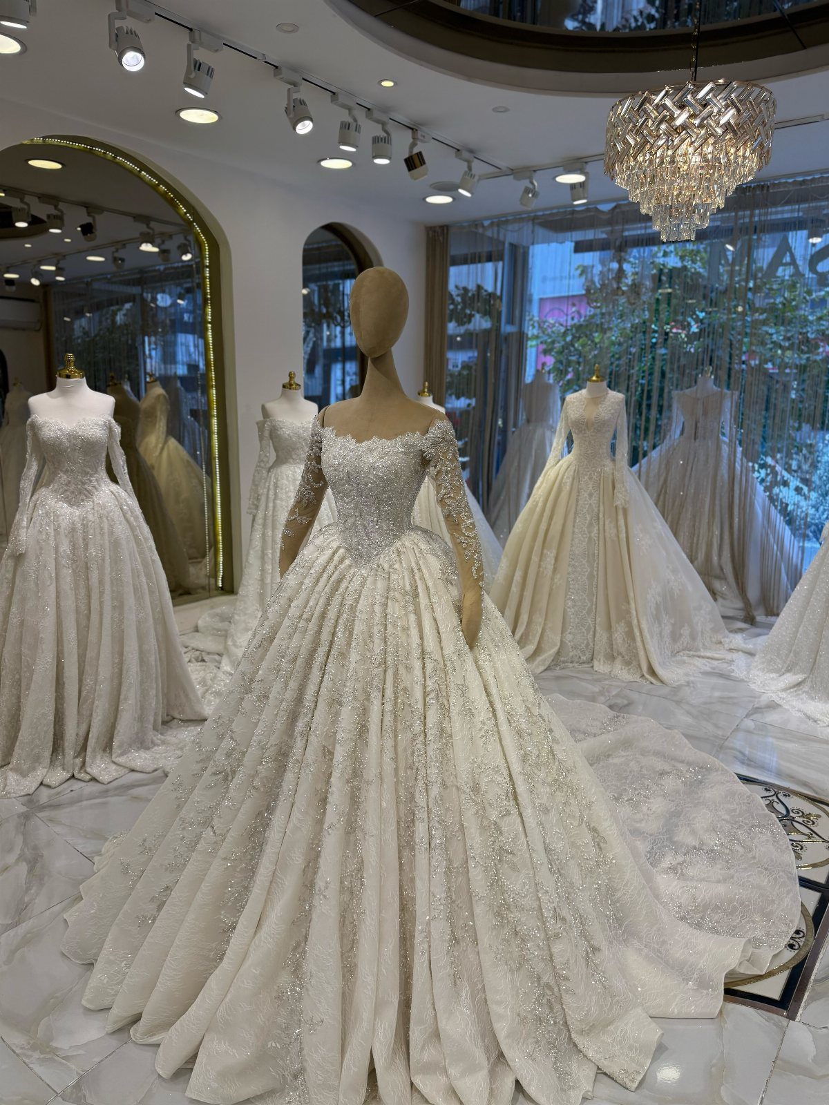 Sparkling white wedding dresses on mannequins in a luxury bridal boutique setting.