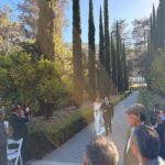Bride in white gown walking down stone aisle escorted by a man