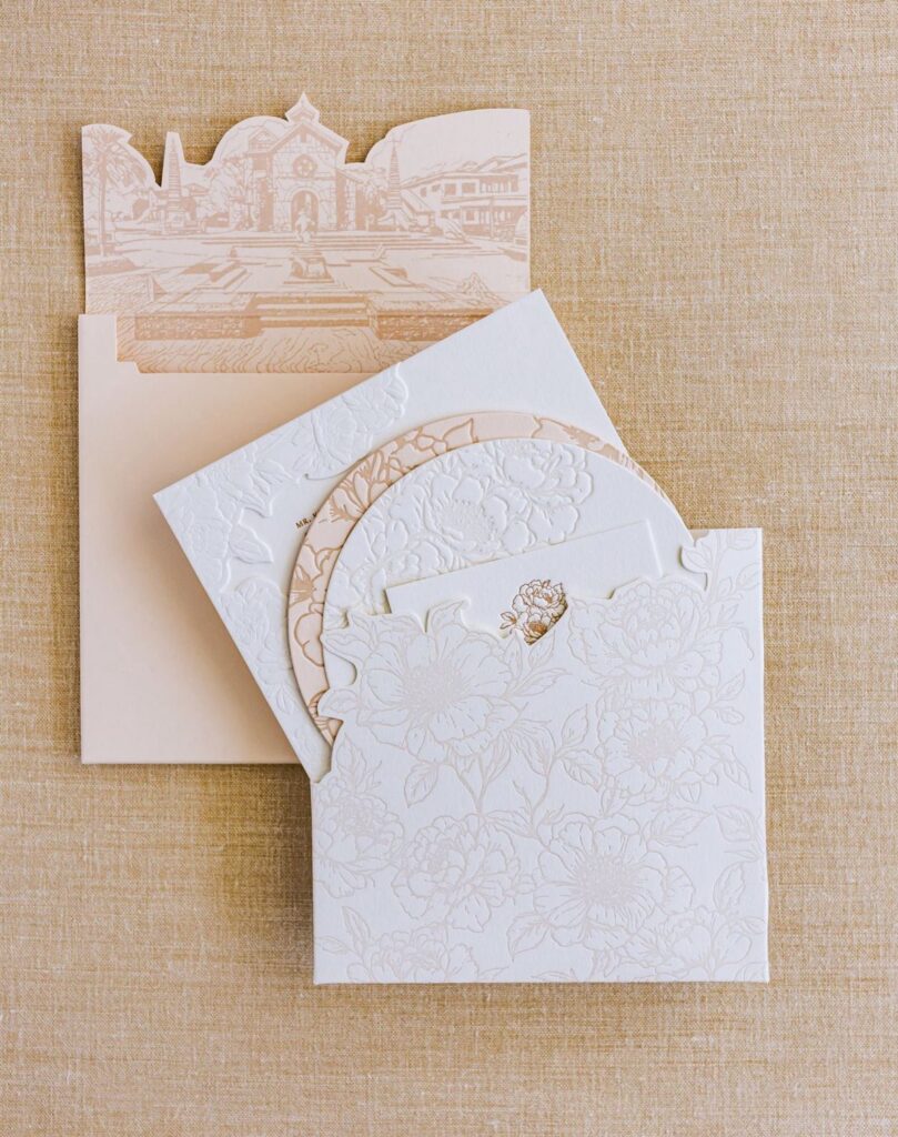 White floral wedding invitation with a circular cutout sleeve and laser-cut card.