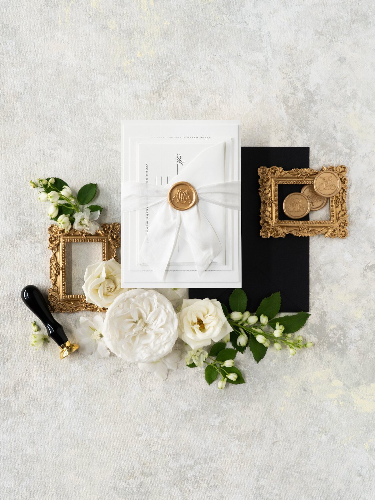 White wedding invitation tied with a white ribbon and gold wax seal