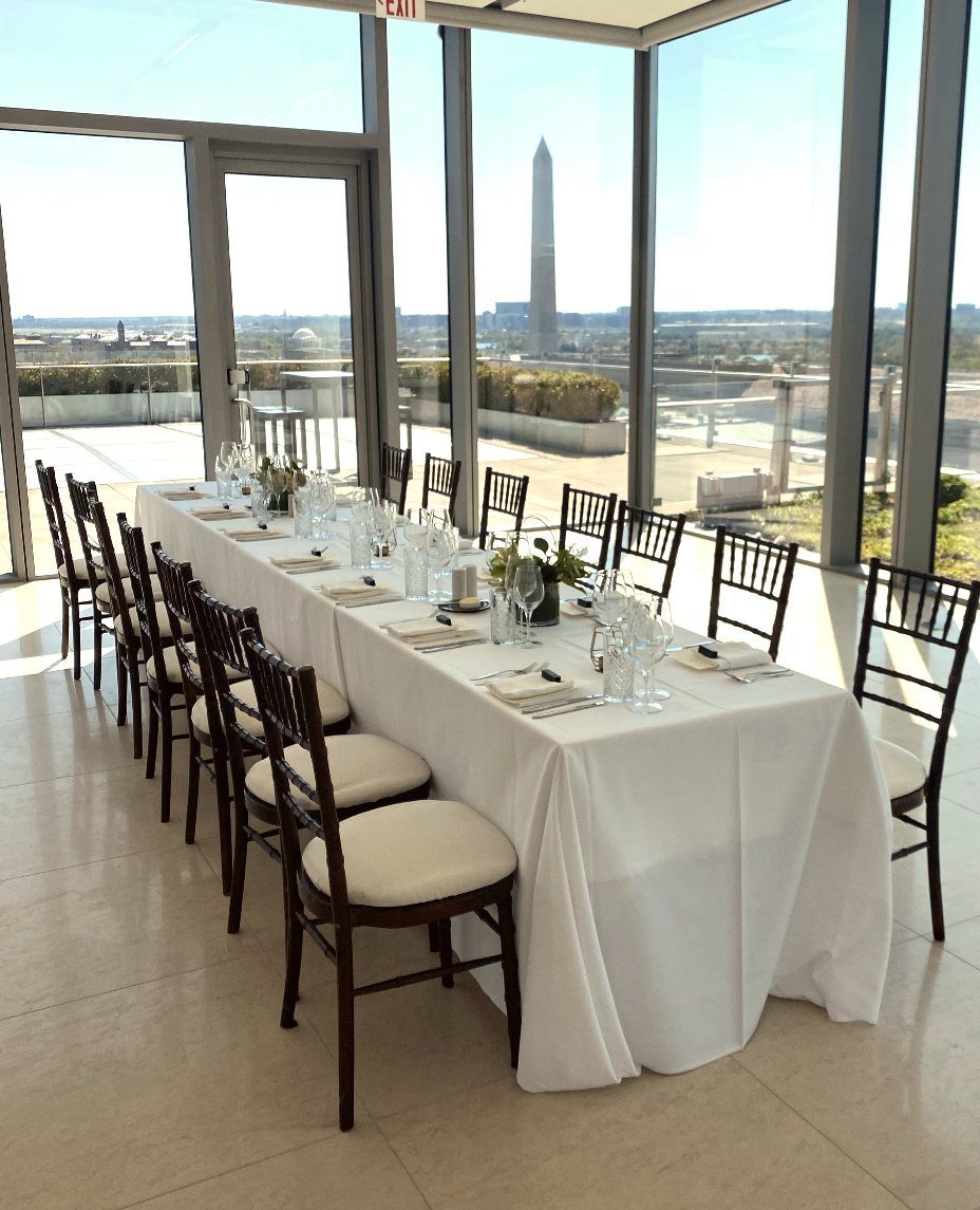 Long white dining table set for a formal event overlooking the Washington Monument.